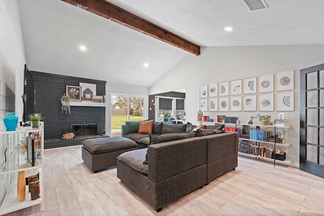 living room with a brick fireplace, beam ceiling, visible vents, and wood finished floors