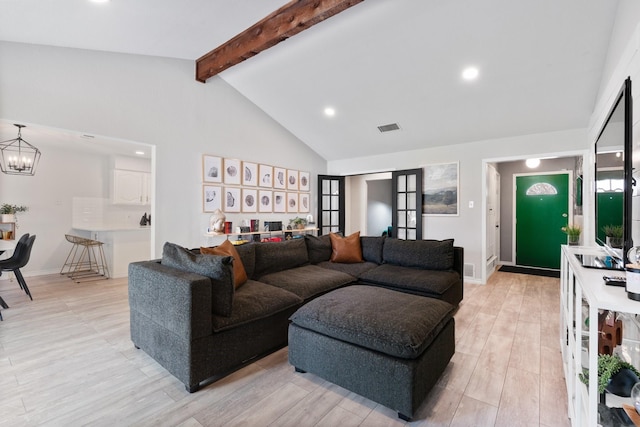 living room featuring a chandelier, beam ceiling, light wood-style flooring, and visible vents