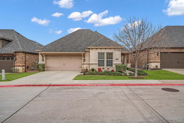 french country home featuring a shingled roof, a front yard, concrete driveway, and brick siding