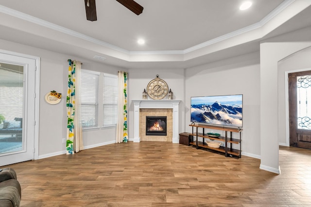 living area with ornamental molding, a tile fireplace, wood finished floors, and baseboards