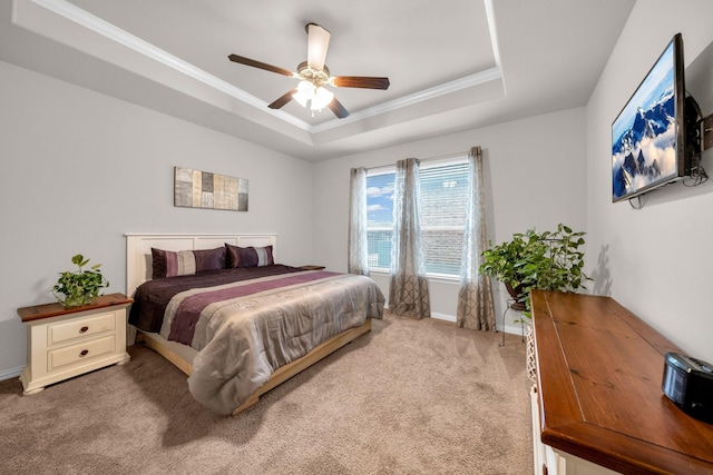 carpeted bedroom with ornamental molding, a tray ceiling, baseboards, and a ceiling fan