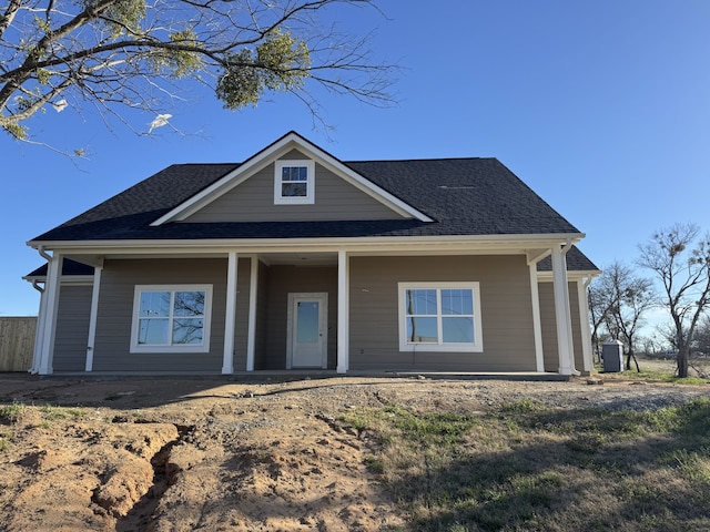 view of front of property with a shingled roof, covered porch, and central AC unit