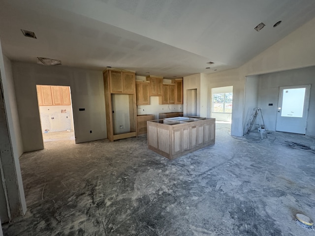 kitchen with a center island, visible vents, vaulted ceiling, and light brown cabinetry