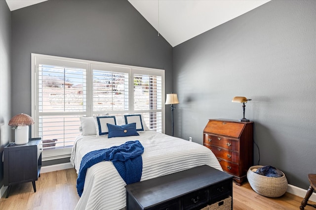 bedroom featuring light wood-type flooring, baseboards, and vaulted ceiling