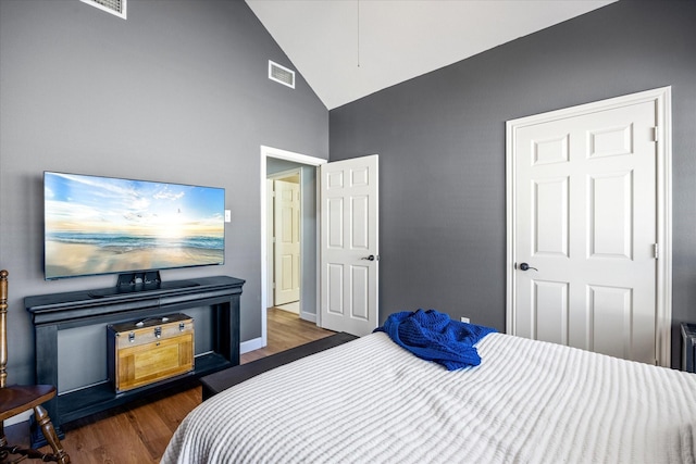 bedroom featuring lofted ceiling, wood finished floors, visible vents, and baseboards