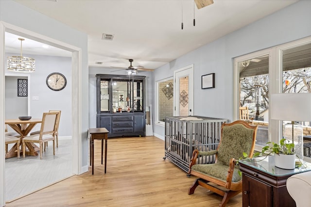 sitting room featuring visible vents, ceiling fan, baseboards, and light wood-style floors