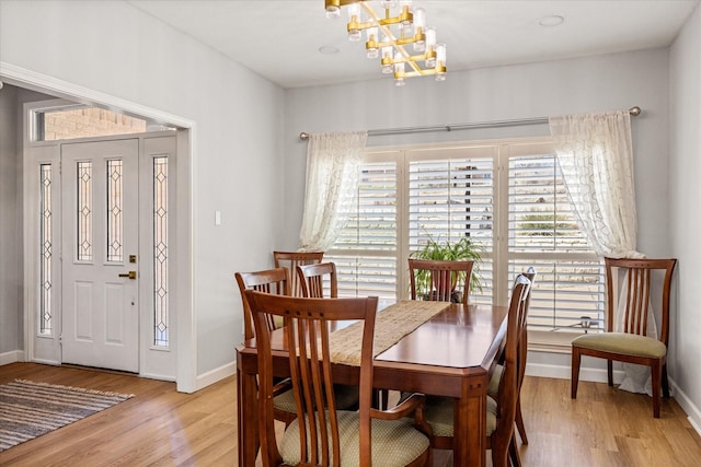 dining area featuring baseboards, a chandelier, and light wood finished floors