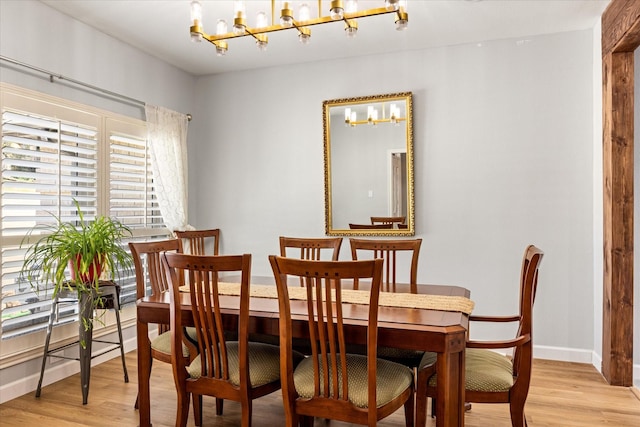 dining area featuring a notable chandelier, light wood-style floors, and baseboards