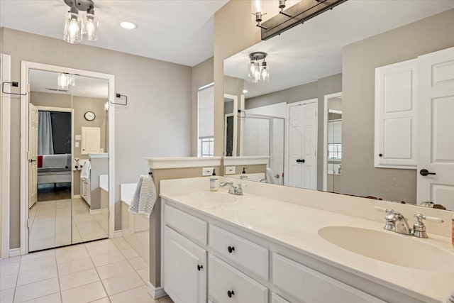 ensuite bathroom with a sink, a stall shower, double vanity, and tile patterned flooring