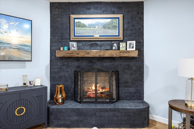 interior details featuring baseboards, a brick fireplace, and wood finished floors