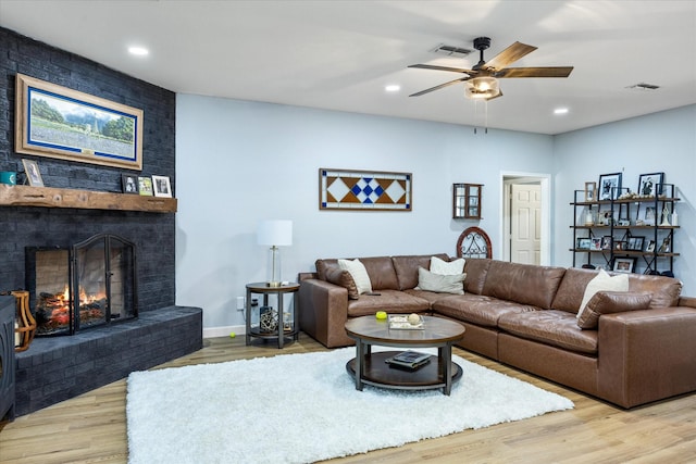 living room featuring recessed lighting, visible vents, a brick fireplace, and light wood-style flooring