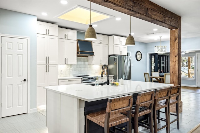 kitchen with backsplash, light countertops, stainless steel appliances, custom exhaust hood, and white cabinetry