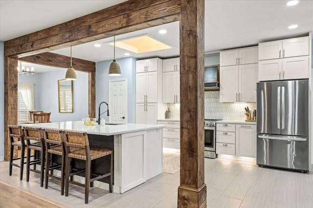 kitchen with beamed ceiling, a sink, white cabinetry, appliances with stainless steel finishes, and decorative backsplash