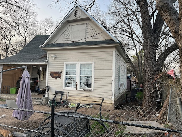 exterior space featuring a fenced front yard, cooling unit, and roof with shingles