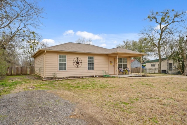 view of front of house with a patio area, fence, and a front lawn