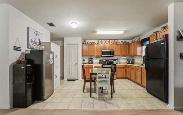 kitchen with light tile patterned floors, visible vents, brown cabinetry, stainless steel appliances, and light countertops