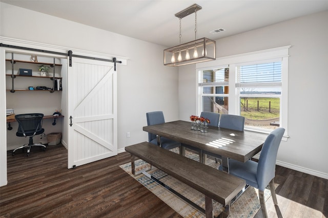 dining room with a barn door, dark wood-type flooring, visible vents, and baseboards