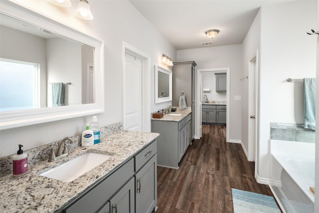 full bathroom with visible vents, a sink, a bath, and wood finished floors