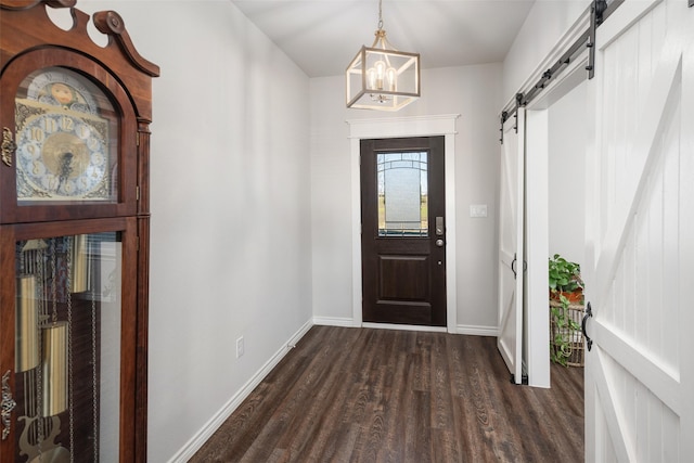 entryway with a barn door, an inviting chandelier, dark wood finished floors, and baseboards