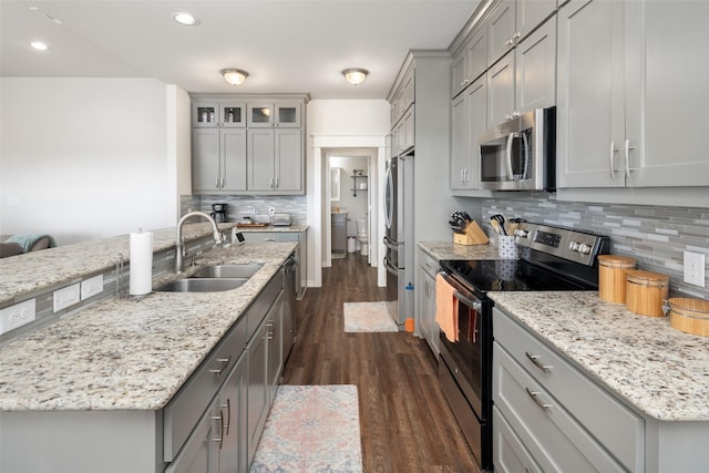 kitchen with tasteful backsplash, dark wood-style floors, appliances with stainless steel finishes, gray cabinetry, and a sink