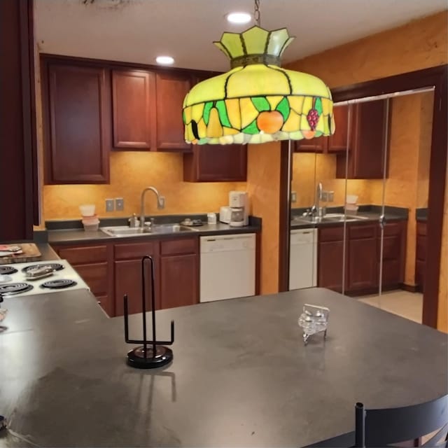 kitchen featuring dark countertops, a sink, and white dishwasher