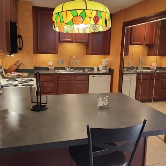 kitchen featuring dark countertops, a sink, black microwave, and white dishwasher