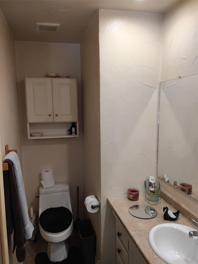 half bath with visible vents, toilet, and vanity