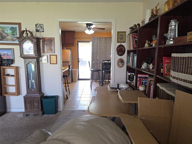 living area featuring a ceiling fan, light tile patterned floors, and light colored carpet