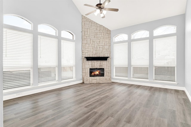 unfurnished living room featuring high vaulted ceiling, a fireplace, wood finished floors, a ceiling fan, and baseboards