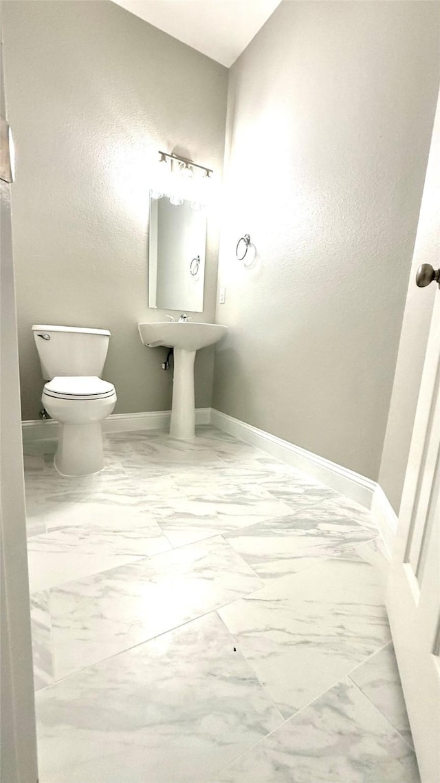 bathroom featuring marble finish floor, toilet, and baseboards