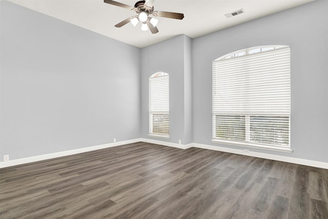 empty room with a healthy amount of sunlight, visible vents, and dark wood finished floors