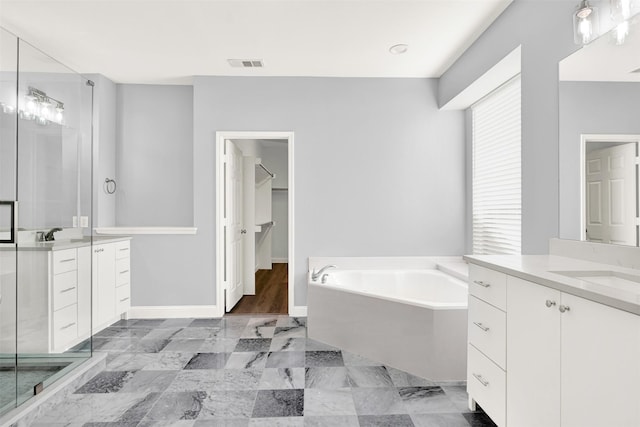 bathroom with two vanities, visible vents, a sink, baseboards, and a bath