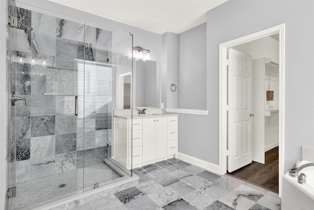 bathroom featuring vanity, baseboards, marble finish floor, a shower stall, and a tub