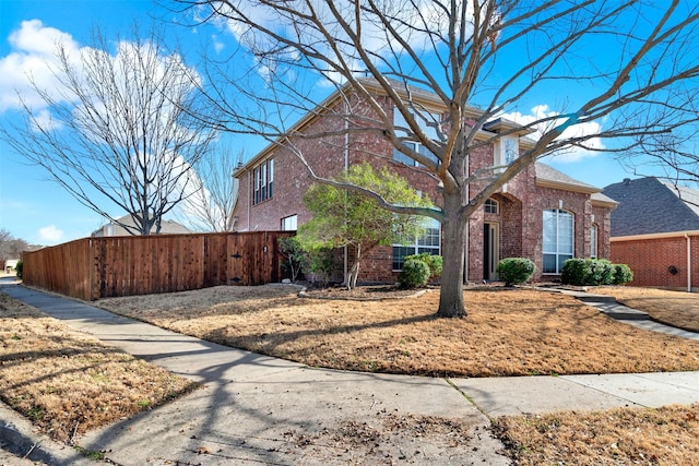 view of front facade featuring fence and brick siding