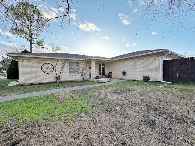 view of front facade featuring a front yard, brick siding, and fence