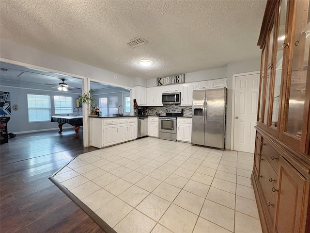 kitchen featuring visible vents, decorative backsplash, white cabinets, dark countertops, and appliances with stainless steel finishes