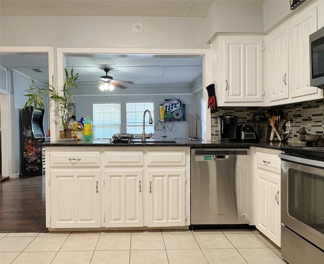 kitchen with appliances with stainless steel finishes, white cabinets, a sink, and light tile patterned floors