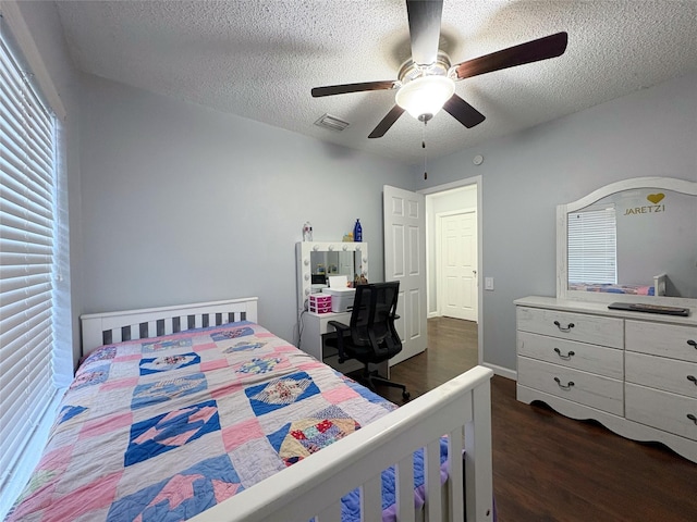 bedroom with a textured ceiling, ceiling fan, dark wood-style flooring, and visible vents