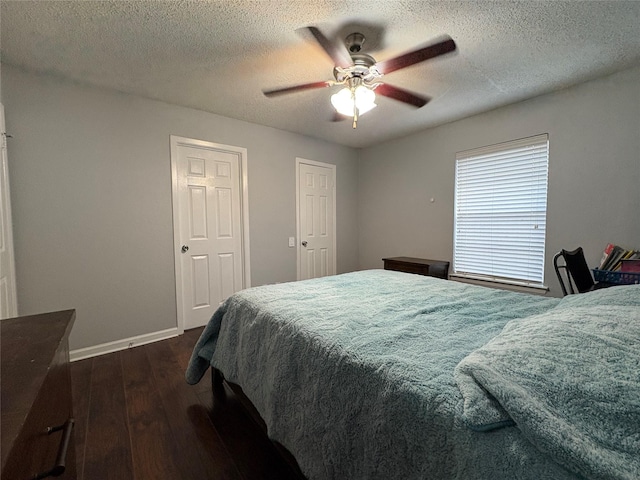 bedroom featuring baseboards, a ceiling fan, dark wood finished floors, and a textured ceiling