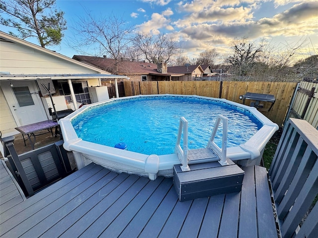 view of swimming pool featuring a fenced backyard, a deck, and a fenced in pool