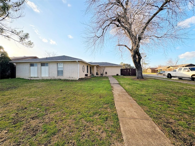 view of front of home featuring a front lawn, fence, and brick siding