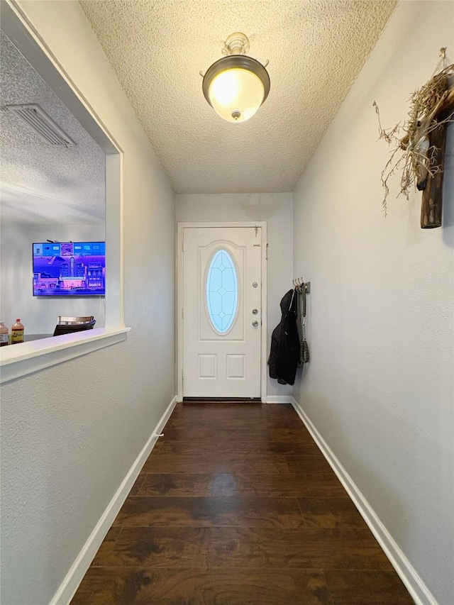 doorway featuring a textured ceiling, baseboards, and wood finished floors