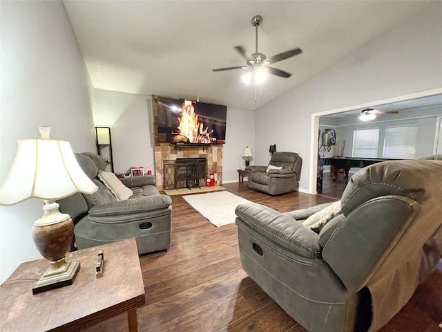 living area with ceiling fan, a fireplace, wood finished floors, baseboards, and vaulted ceiling