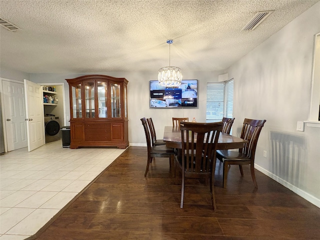 dining room featuring light wood-type flooring, washer / clothes dryer, visible vents, and an inviting chandelier