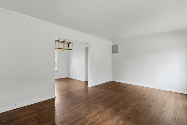 spare room with visible vents, baseboards, wood finished floors, and crown molding