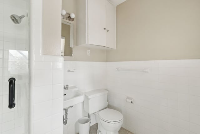 bathroom with a wainscoted wall, a shower, toilet, and tile walls