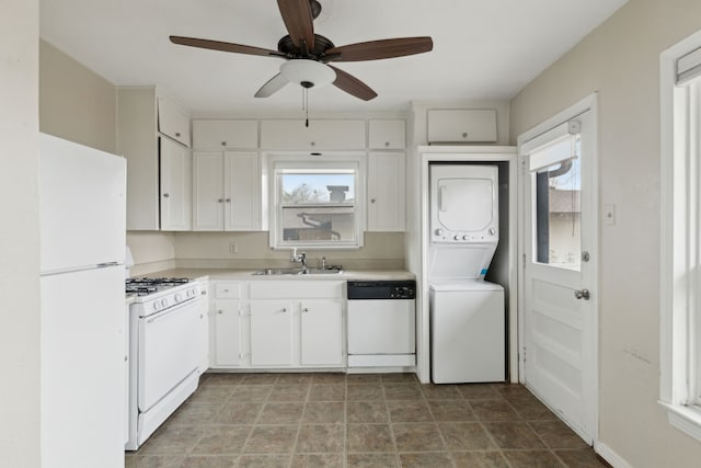 kitchen featuring a sink, white appliances, white cabinets, light countertops, and stacked washer / dryer