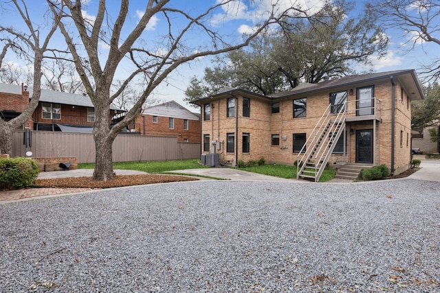 view of front of home featuring stairs, cooling unit, fence, and brick siding