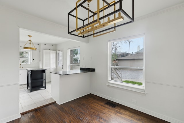 kitchen featuring hanging light fixtures, visible vents, crown molding, and wood finished floors