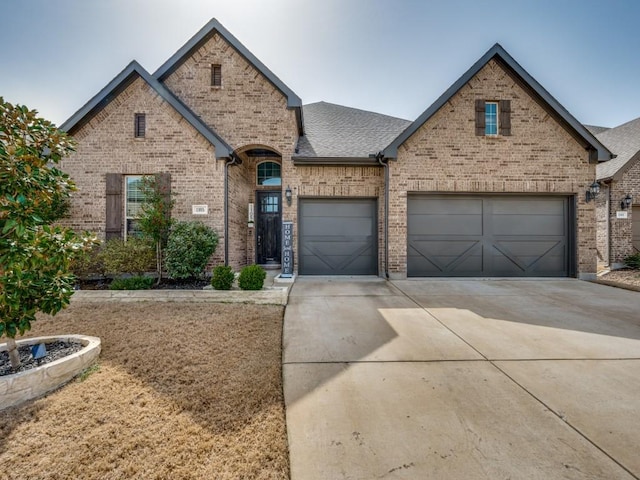 view of front facade with concrete driveway, brick siding, roof with shingles, and an attached garage